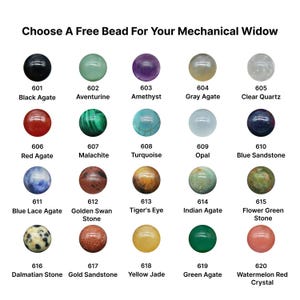May include: A selection of twenty gemstone beads in various colors, including black agate, amethyst, turquoise, and tiger's eye. Each bead is numbered and labeled with its corresponding stone type. The text "Choose A Free Bead For Your Mechanical Widow" is at the top.