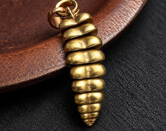 May include: A gold-toned metal pendant shaped like a rattlesnake rattle, featuring a series of stacked, rounded segments that taper toward the bottom, topped with a circular bail for attachment to a necklace chain.