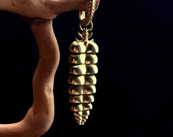 May include: A gold-colored pendant with a segmented, cone-like design. The pendant is suspended from a gold chain and is displayed against a dark background. The segmented design gives the pendant a unique, textured appearance. The jewelry is likely a necklace or earring.