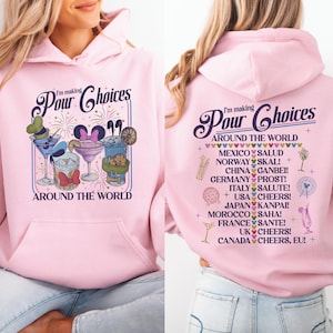 May include: Pink hooded sweatshirt with the text "I'm making Pour Choices" and "Around the World". The front features cocktail illustrations. The back lists international cheers.
