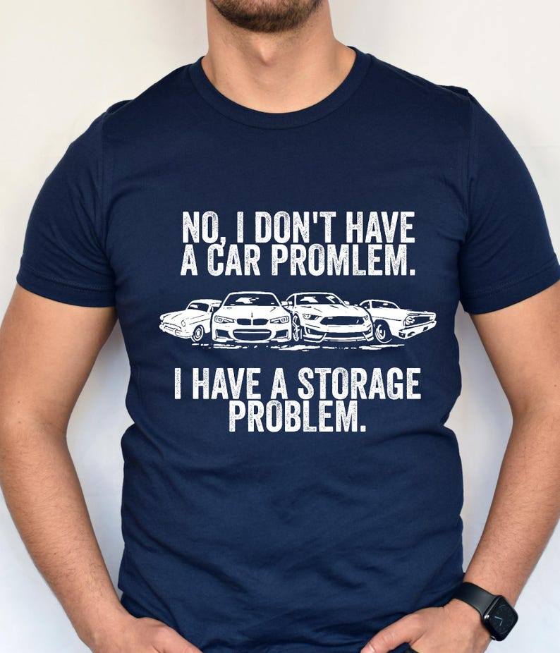 May include: Navy blue t-shirt with white text and car graphics. The text reads "NO, I DON'T HAVE A CAR PROBLEM. I HAVE A STORAGE PROBLEM."