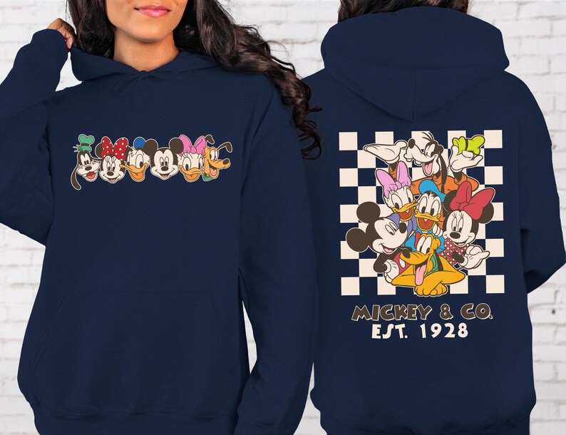 Puede incluir: Sudadera con capucha azul marino con un dise&ntilde;o de personajes de Disney en la parte delantera. La parte trasera muestra un grupo de personajes sobre un fondo a cuadros, con "Mickey & Co. Est. 1928" impreso debajo. La sudadera tiene capucha con cord&oacute;n y bolsillo delantero.