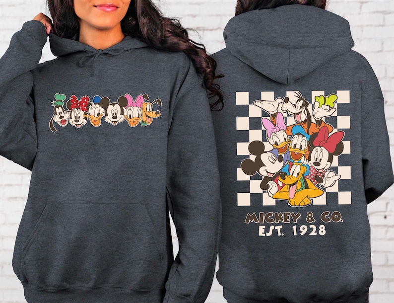 Puede incluir: Sudadera con capucha gris oscuro con un gr&aacute;fico colorido de personajes de dibujos animados en el pecho y la espalda. El gr&aacute;fico frontal incluye a Mickey Mouse, Minnie Mouse, Donald Duck, Daisy Duck, Goofy y Pluto. El gr&aacute;fico trasero est&aacute; sobre un fondo a cuadros con el texto "Mickey & Co. Est. 1928."