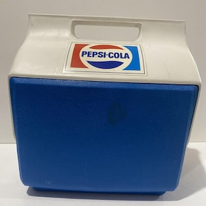 May include: A vintage Pepsi-Cola cooler with a white top and a blue base. The cooler features a handle and a Pepsi-Cola logo on the front. The logo is red, white, and blue.