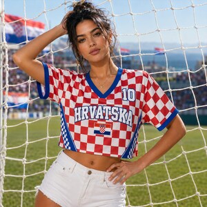 Puede incluir: Un top corto de cuello en V con estampado de cuadros rojos y blancos y ribetes azules. La prenda incluye el texto HRVATSKA en letras azules, el n&uacute;mero 10 en azul y un peque&ntilde;o emblema de la bandera croata. Los laterales tienen paneles azules a cuadros.