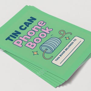 May include: A stack of green notebooks with the words "TIN CAN Phone Book" in blue and pink. The cover features a cartoon tin can phone illustration and the text "THIS BOOK BELONGS TO".