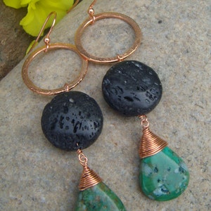 May include: Copper earrings with black lava rock and green gemstone drops. The earrings have a hammered copper hoop and a copper wire wrapped around the gemstone.