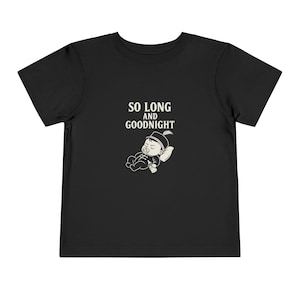 Może przedstawiać: Czarny t-shirt dla malucha z napisem "SO LONG AND GOODNIGHT" nad kreskówkową ilustracją śpiącego dziecka w kapeluszu i ze smoczkiem. Dziecko leży na poduszce.