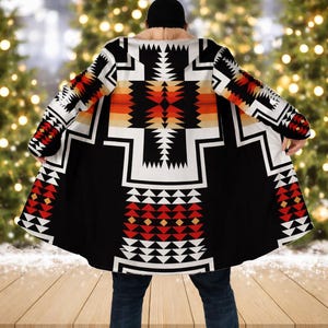 Pode incluir: Capa estampada em preto, branco, vermelho e laranja. A capa apresenta um design geométrico e uma gola de pele sintética creme. É até o joelho com mangas compridas. O design é inspirado em padrões nativos americanos.