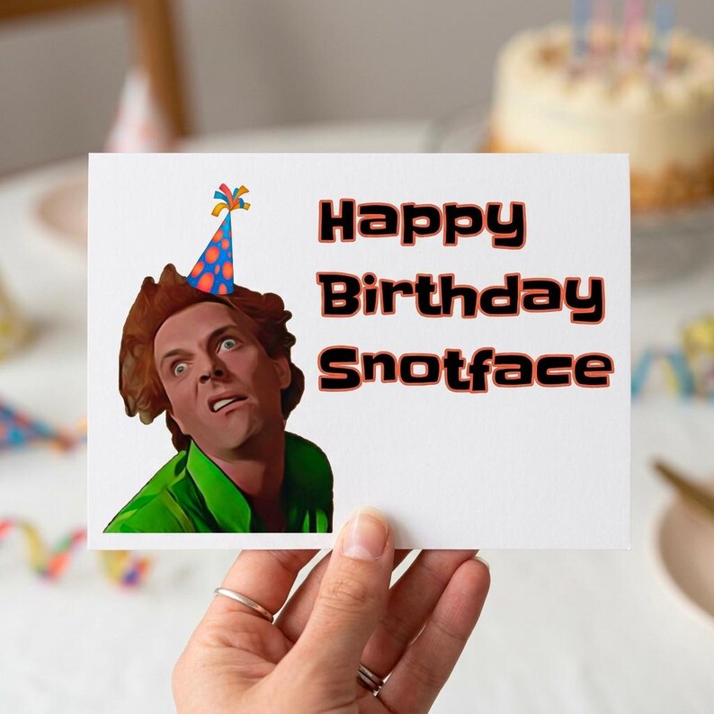 Puede incluir: Una tarjeta de felicitaci&oacute;n blanca con el texto "Happy Birthday Snotface" en negro y rojo. La tarjeta presenta una imagen de dibujos animados de una persona con un gorro de fiesta y una camisa verde.