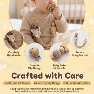 Op de afbeelding: Een babyspeen met een houten clip en een gehaakt giraffendesign. De speen is bevestigd aan een houten kralenketting met letters. De tekst "Crafted with Care" is inbegrepen.