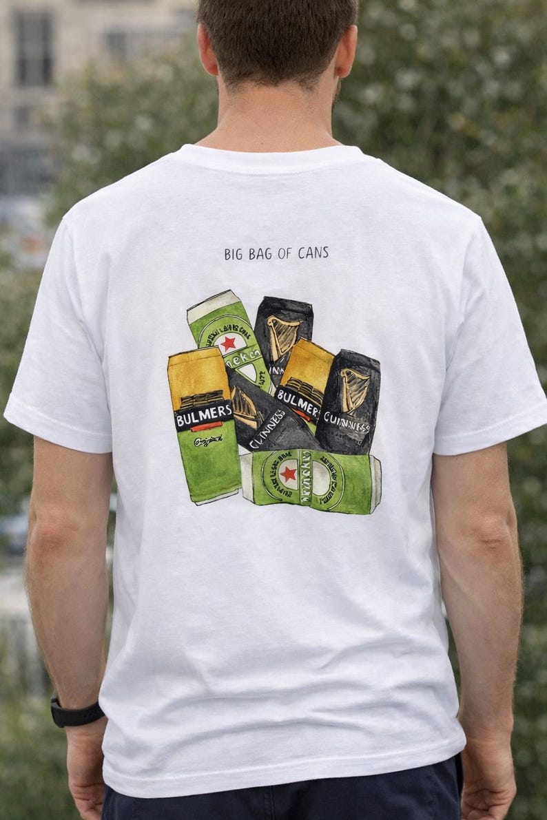 Pu&ograve; includere: T-shirt bianca con una grafica di diverse lattine di birra e sidro, tra cui Heineken, Guinness e Bulmers. Il testo "BIG BAG OF CANS" &egrave; stampato sopra le lattine.