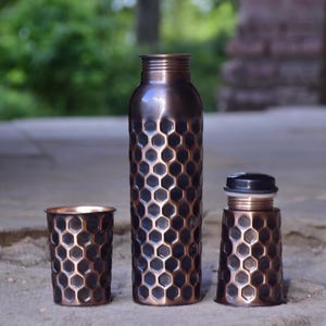 Elegant handmade copper bottle with unique honeycomb engraving and copper glass, premium eco-friendly drinkware set.