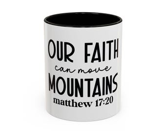 May include: White ceramic mug with a black interior. The mug features the text "OUR FAITH can move MOUNTAINS matthew 17:20" in black lettering. The mug is a standard size and shape, suitable for hot or cold drinks.