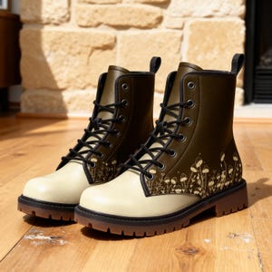 May include: A pair of olive green and cream-colored combat boots with black laces. The boots feature a mushroom pattern on the side and a brown sole. The boots are made of leather-like material.