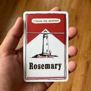 May include: A rectangular sticker featuring a red and white design with a black lighthouse illustration. The text reads I have my qualms, Widow's Bay, and Rosemary in black and red lettering. The sticker has a white border and a hand-drawn style.