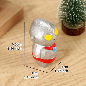 May include: A silver-colored figurine of a character with yellow eyes and a red and blue accent. The figurine is 2.56 inches tall, 1.18 inches wide, and 1.57 inches deep. The figurine is on a wooden surface.