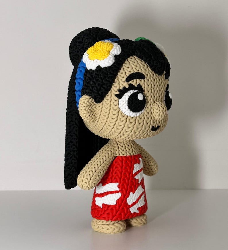 Puede incluir: Mu&ntilde;eca hecha a mano con cara y cuerpo bronceados, cabello negro y un vestido rojo con detalles blancos. La mu&ntilde;eca tiene ojos negros grandes y una flor en el pelo. La mu&ntilde;eca est&aacute; sobre una superficie blanca.