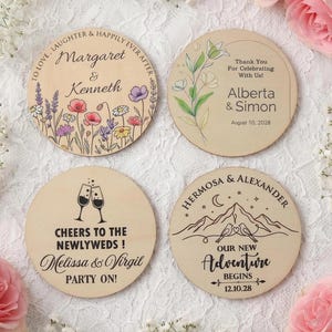 Puede incluir: Cuatro posavasos redondos de madera con texto y diseños personalizados. Uno presenta ilustraciones florales y los nombres "Margaret & Kenneth". Otro dice "Alberta & Simon" con una fecha. El tercero dice "Melissa & Virgil". El último dice "Hermosa & Alexander."