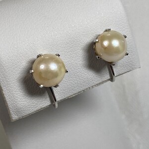 May include: A pair of silver clip-on earrings with a single round pearl on each earring.