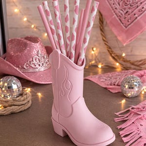 May include: A white ceramic mug with a black handle and the text "But First, Coffee" in a bold, black font. The mug is set against a neutral background, highlighting its simple design.