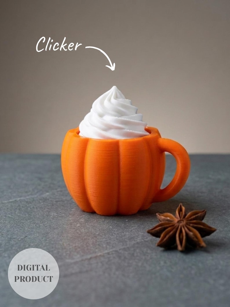 K&ouml;nnte beinhalten: Ein orangefarbener, k&uuml;rbisf&ouml;rmiger Becher mit Henkel, gekr&ouml;nt von einem Wirbel aus wei&szlig;er Schlagsahne. Das Bild enth&auml;lt den Text Clicker mit einem Pfeil zum Becher und ein kreisf&ouml;rmiges Abzeichen mit der Aufschrift DIGITAL PRODUCT. Ein Sternanis liegt daneben.