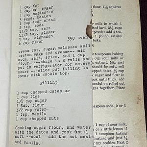 May include: A vintage recipe for Molasses Cookies, with ingredients like molasses, eggs, and spices, is handwritten on a torn piece of paper. The recipe includes instructions for the cookie filling.