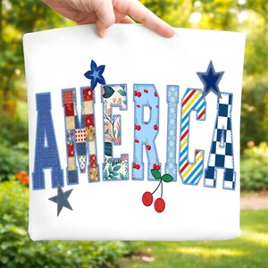 Puede incluir: Bolso de mano blanco con la palabra "AMERICA" en un diseño de patchwork. Las letras presentan varios patrones, incluyendo diseños florales, de cerezas y a rayas. También se incluyen estrellas azules y cerezas.