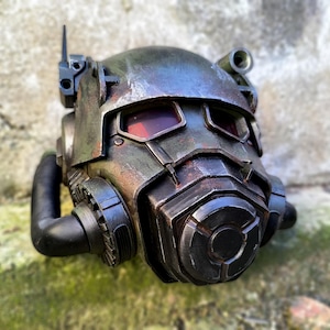 May include: A weathered, metallic helmet with a futuristic design. The helmet features red-tinted eye lenses, a prominent front respirator, and various mechanical details. The color scheme includes shades of gray, brown, and hints of rust, suggesting a post-apocalyptic theme.