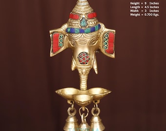 Brass Ganesha wall hanging with oil and wick lamp and bells.