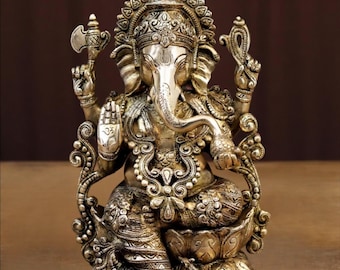 Könnte beinhalten: Eine detaillierte, silberfarbene Statue der hinduistischen Gottheit Ganesha, die auf einer Lotusblume sitzt. Die Statue weist aufwendige Schnitzereien, einen großen Rüssel und mehrere Arme auf, die verschiedene symbolische Objekte halten. Der Hintergrund ist ein warmes Braun.