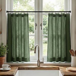 Könnte beinhalten: Ein Küchenfenster mit zwei grünen Leinen-Vorhängen. Die Vorhänge hängen an einer schwarzen Stange. Ein weißes Waschbecken, eine Holz-Arbeitsplatte und verschiedene Küchenartikel sind sichtbar.