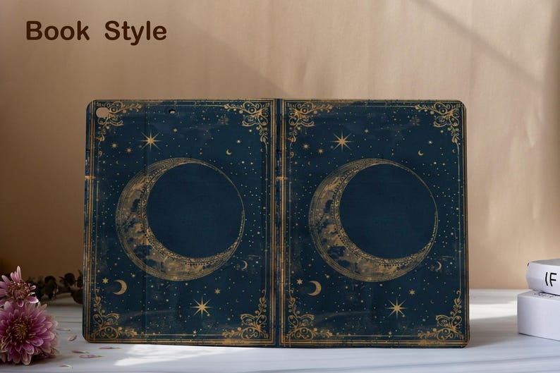 May include: A dark blue book-style case with a celestial design. The case features a large crescent moon and stars in gold, with decorative gold borders. The text "Book Style" is at the top.