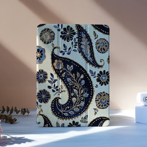 Op de afbeelding: Een tablethoes met een crèmekleurige achtergrond en een marineblauw paisley patroon. Het ontwerp bevat bloemen- en bladmotieven. De hoes staat rechtop op een wit oppervlak.