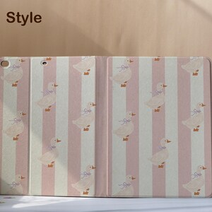 May include: A tablet case with a pink and white striped pattern. The case features a repeating pattern of ducks with blue bows. The words "Book Style" are in the upper left corner.