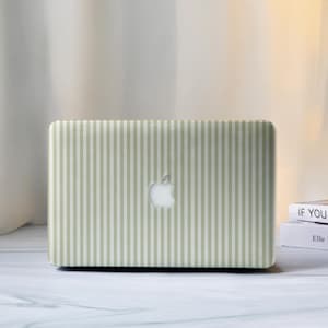 May include: A laptop with a light green and white striped design. The laptop has a white Apple logo in the centre. The laptop is on a white surface.