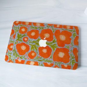 Puede incluir: Una funda para portátil con un diseño floral de amapolas naranjas con centros amarillos y hojas verdes sobre un fondo azul claro. El logotipo de Apple es visible. De forma rectangular.