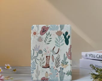 May include: A rectangular white tablet case featuring a repeating pattern of desert-themed illustrations including brown cowboy boots, pink cowboy hats, various green cacti, succulents, orange suns, and floral elements in muted pastel tones.