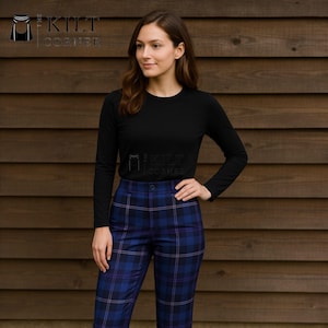 May include: A woman wearing a black long-sleeve shirt and blue plaid pants. The pants have a blue and purple plaid pattern. The logo "Kilt Corner" is visible in the upper left and center of the image.
