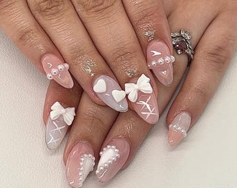 Uñas postizas de corazón de ángel: lazo 3D, perla y detalle de ala