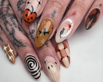 May include: A set of almond-shaped, painted fingernails with Halloween-themed designs. The nails feature a pumpkin, a ghost, a black cat on a crescent moon, and other abstract patterns in orange, brown, black, and white.