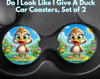 May include: Set of two car coasters featuring a cartoon duck with large green eyes and an orange beak. The coasters have a blue sky background with frogs and the text "Do I look like I give a DUCK?!"