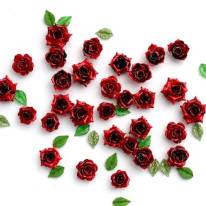 Peut inclure: Une collection de petites roses rouges avec des feuilles vertes et dorées parsemées sur une surface blanche. Les roses ont une finition brillante et sont disposées de manière aléatoire, idéales pour les projets d'artisanat.