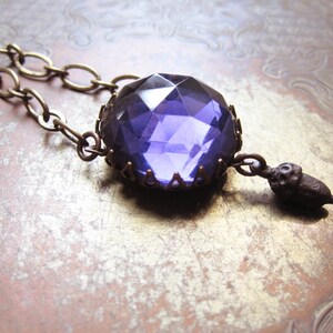 May include: A purple glass pendant necklace with a bronze chain and an acorn charm.
