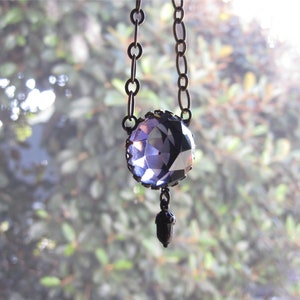 May include: A purple crystal pendant necklace with a silver chain and an acorn charm.