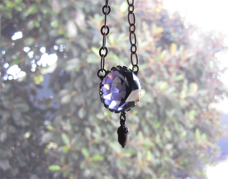 May include: A purple crystal pendant necklace with a silver chain and an acorn charm.