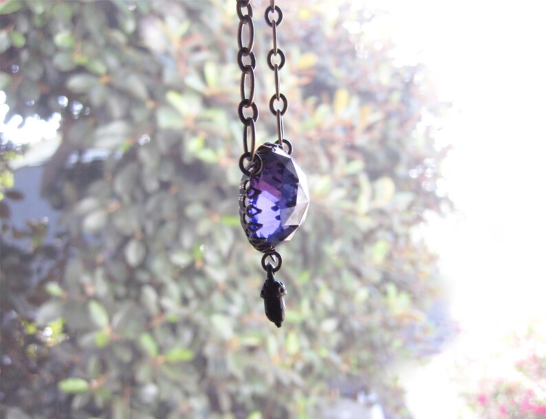 May include: A purple crystal pendant necklace with a silver chain and a small acorn charm.