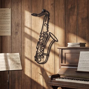 Puede incluir: Un adorno de pared de metal negro con forma de saxofón, montado en una pared de madera. El saxofón es un contorno detallado, que muestra las curvas y las llaves del instrumento. El fondo incluye un piano, partituras y un atril.