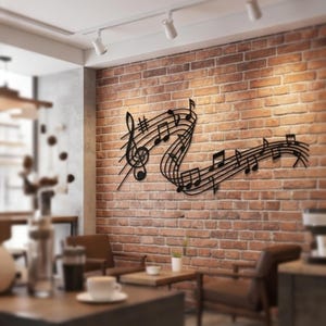 Può includere: Un'opera d'arte da parete in metallo nero raffigurante note e simboli musicali, tra cui una chiave di violino e una serie di note su un pentagramma. L'arte è montata su un muro di mattoni rossi, creando un contrasto di trame e colori. Il pezzo aggiunge un tema musicale alla stanza.