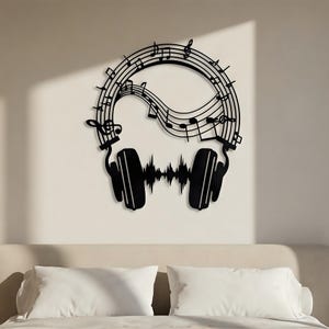 May include: Black metal wall art featuring a musical theme. The design includes a pair of headphones, musical notes, and a sound wave. The artwork is mounted on a white wall above a bed with white pillows.